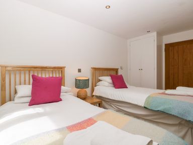 A bedroom with two single beds wooden headboards bedside table with lamp and white closet doors at Owl Barn in Marston Stannett near Leominster