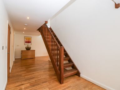 A hallway with wooden stairs and wooden chest with basket at Owl Barn in Marston Stannett near Leominster
