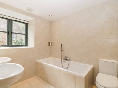 A bathroom with a bathtub toilet two sinks and a window at Owl Barn in Marston Stannett near Leominster