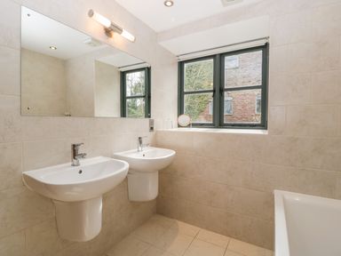 A bathroom with two wall-mounted sinks a large mirror a window and a bathtub at Owl Barn in Marston Stannett near Leominster