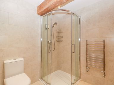 A bathroom with a glass shower enclosure a toilet and a wall-mounted towel radiator at Owl Barn Marston Stannett near Leominster