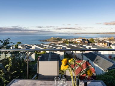 A balcony with chairs and sunflowers overlooking a caravan park and the sea at Lanyon in St Ives