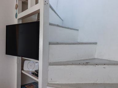 A staircase with a TV mounted on the wall at Ivy Cottage Trenale near Tintagel