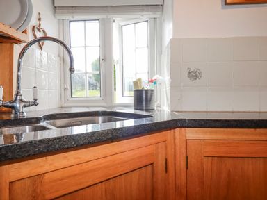 A kitchen with a sink and windows at Ivy Cottage in Trenale near Tintagel