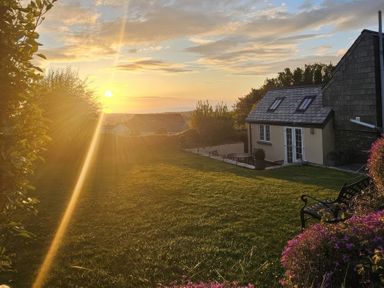 A sunset over a garden with a house at Ivy Cottage, Trenale near Tintagel
