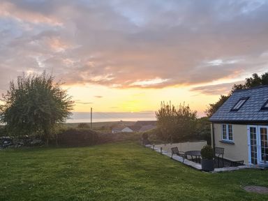 A garden with a house and table at Ivy Cottage in Trenale near Tintagel