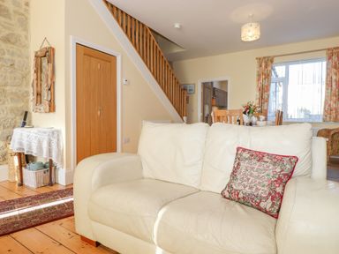 A living room with a white leather sofa and wooden stairs at Southview Amble in Amble