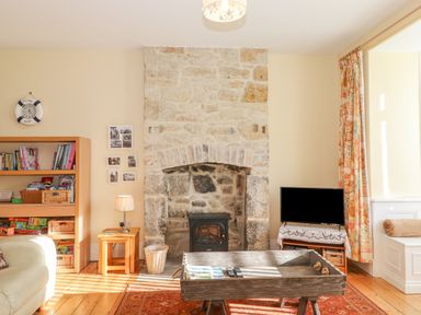 A living room with a stone fireplace a wooden bookshelf and a television at Southview Amble in Amble