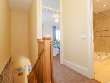 A stairway with wooden railing leading to a hallway with doors to a bedroom and a bathroom at Southview Amble in Amble