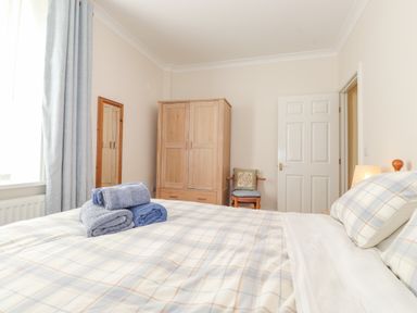 A bedroom with a bed folded towels on it a wooden wardrobe a chair and a mirror at Southview Amble in Amble