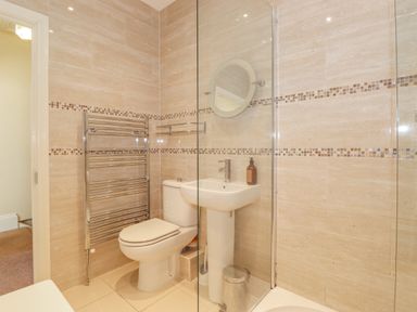 A bathroom with a toilet sink mirror heated towel rack and a glass shower enclosure at Southview Amble in Amble