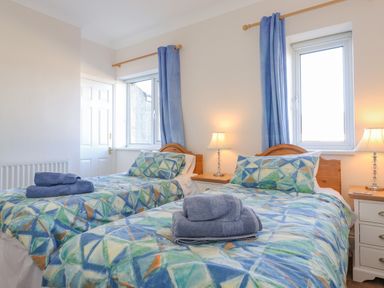 A bedroom with two single beds with patterned bedding and blue curtains at Southview Amble in Amble