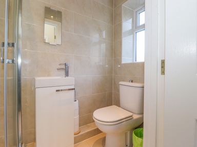 A bathroom with a toilet sink and a small window at Southview Amble in Amble