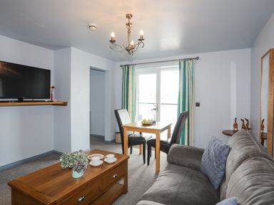A living room with a grey sofa a wooden coffee table two black chairs and a wooden dining table at Tegid Lakeside - Bala Lake in Bala