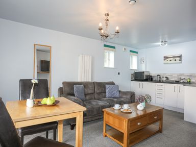 A living room with a sofa a coffee table and a dining table next to a kitchen at Tegid Lakeside - Bala Lake in Bala