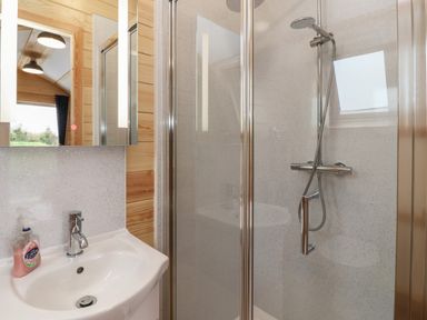A bathroom with a sink and faucet a shower with a glass door and a showerhead at Mischief in Little Kelk near Bridlington