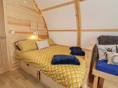 A bedroom with a wooden double bed with yellow patterned bedding and blue towels at Mischief in Little Kelk near Bridlington