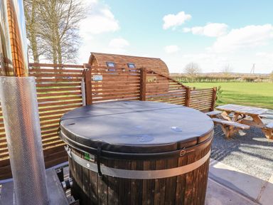 An outdoor area with a round covered hot tub wooden fence picnic tables and a field at Mischief in Little Kelk near Bridlington