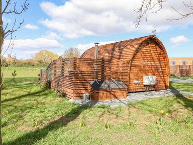 A curved wooden cabin with a fenced area and grassy surroundings at Mischief in Little Kelk near Bridlington
