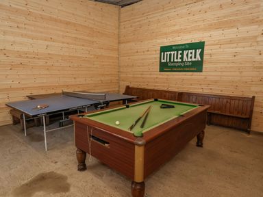 A room with a pool table and a ping pong table with wooden bench seating at Mischief in Little Kelk near Bridlington