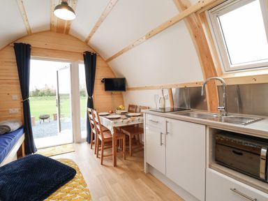 A small kitchen and dining area with a table set for four chairs and a door opening to a grassy outdoor area at Covey in Little Kelk near Bridlington