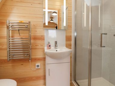 A bathroom with a sink cabinet mirror towel radiator and glass shower at Covey in Little Kelk near Bridlington
