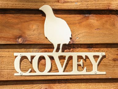 A metal sign with a bird shape above the word Covey mounted on wooden planks