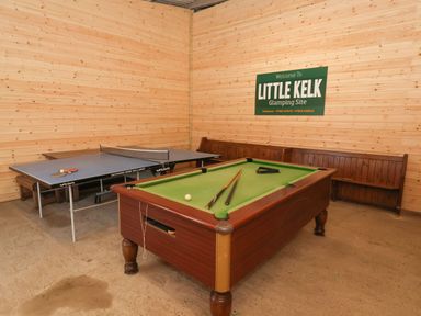 A game room with a pool table and a ping pong table with wooden benches at Little Kelk Glamping Site