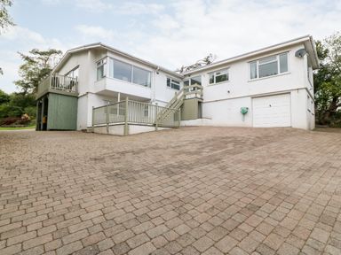 A large white house with multiple windows a balcony and a paved driveway at Willoway in Benllech