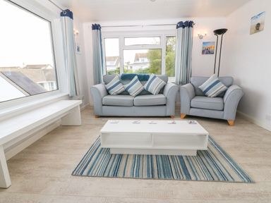 A living room with two sofas a white coffee table a striped rug and large windows at Willoway in Benllech