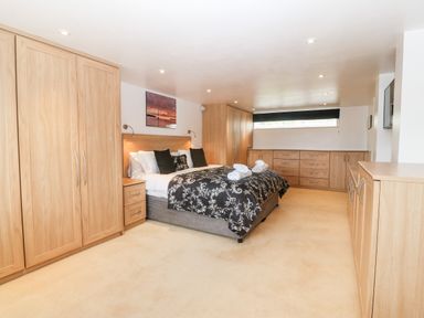 A bedroom with a double bed black and white bedding wooden wardrobes and drawers at Willoway in Benllech