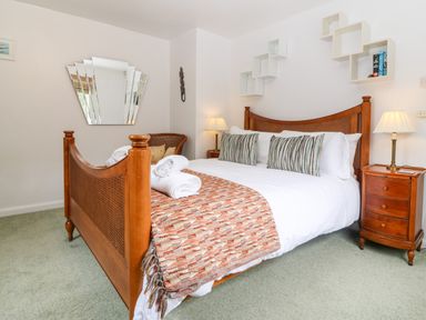 A bedroom with a wooden bed with white bedding and pillows next to bedside tables with lamps at Willoway in Benllech