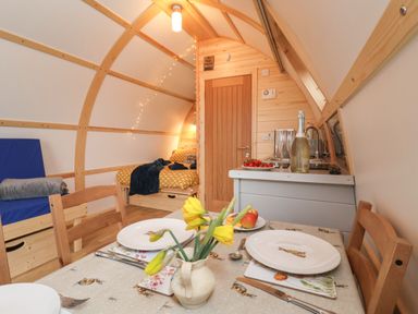 A small dining area with a table set for two and a kitchenette in a wooden pod at Bouquet in Little Kelk near Bridlington