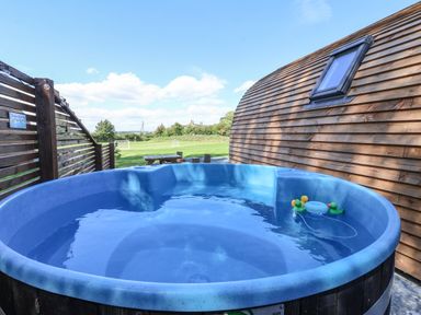 An outdoor hot tub with floating rubber ducks next to a wooden building and a picnic table at Bouquet in Little Kelk near Bridlington