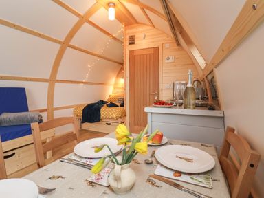 A dining table set with plates and flowers in a small wooden room with a bed and kitchenette at Bevy in Little Kelk near Bridlington