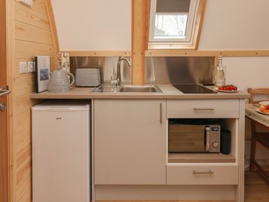 A compact kitchen area with a small fridge sink microwave and countertop appliances at Bevy in Little Kelk near Bridlington