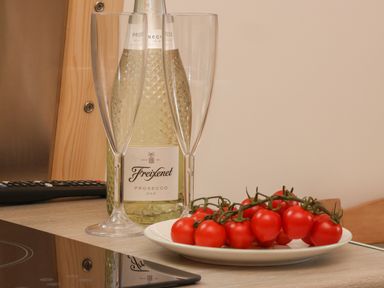 A kitchen counter with a bottle of Freixenet prosecco two champagne glasses and a plate of cherry tomatoes