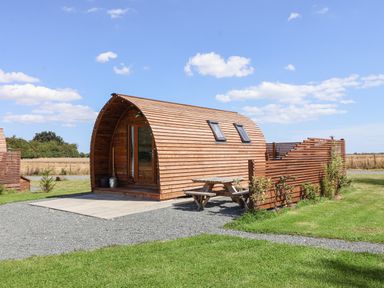 A wooden cabin with curved roof and picnic table outside in a grassy area at Bevy in Little Kelk near Bridlington