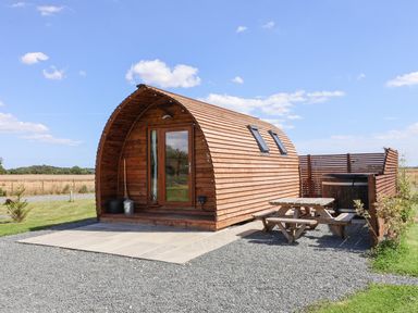 A wooden pod structure with glass door picnic table and hot tub outside at Bevy in Little Kelk near Bridlington