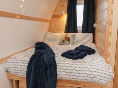 A bedroom with a bed covered in patterned bedding a pillow with a rabbit image and dark curtains at Husk in Little Kelk near Bridlington