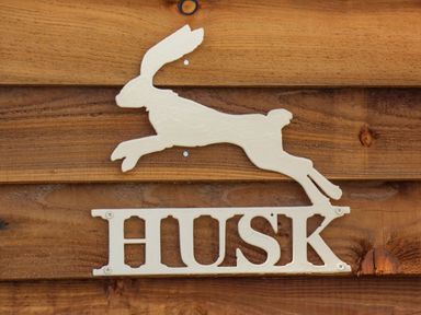 A metal sign shaped like a running hare with the word HUSK mounted on wooden boards at Husk Little Kelk near Bridlington