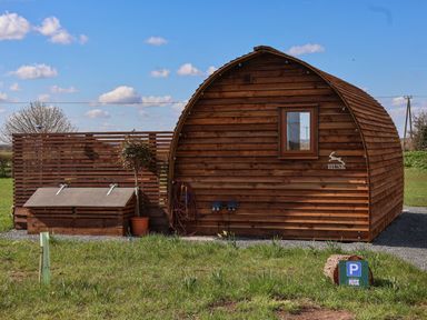 A wooden cabin with a small window and a parking sign on the grass at Husk in Little Kelk near Bridlington