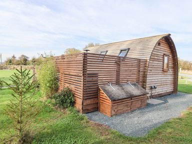A wooden cabin with a slatted wooden fence and garden shed on a gravel path in a grassy area at Husk in Little Kelk near Bridlington