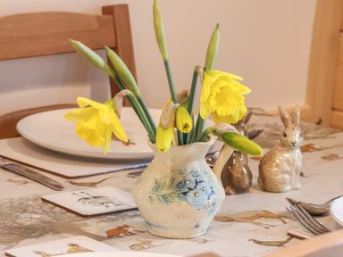 A table with a ceramic jug holding yellow daffodils and ceramic rabbit decorations at Parliament in Little Kelk near Bridlington