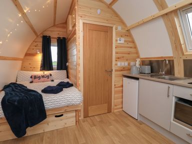 A compact wooden room with a bed on the left and a kitchenette on the right at Parliament in Little Kelk near Bridlington