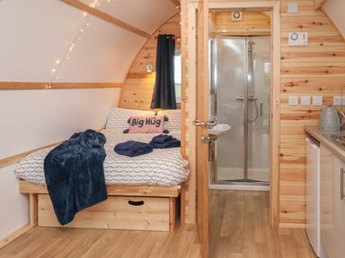 A small bedroom with a bed and a blanket next to a bathroom with a shower and wooden walls at Parliament Little Kelk near Bridlington