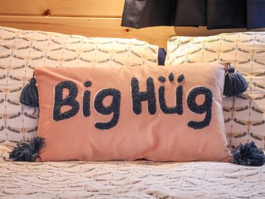 A bed with a pink pillow embroidered with the words Big Hug on patterned sheets at Parliament in Little Kelk near Bridlington