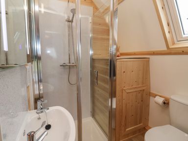 A bathroom with a shower enclosure a sink a toilet and wooden storage at Parliament in Little Kelk near Bridlington