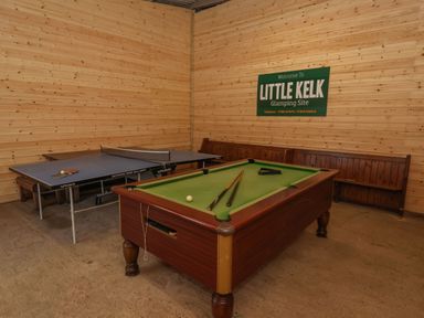 A game room with a pool table and a ping pong table and a bench against a wooden wall at Little Kelk near Bridlington