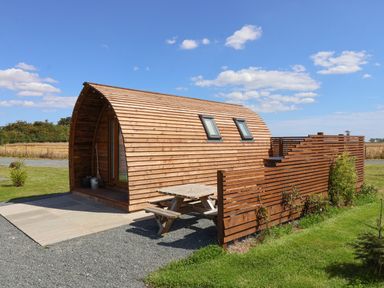 A small wooden cabin with two skylight windows a picnic table and a wooden fence on a grassy area at Parliament in Little Kelk near Bridlington